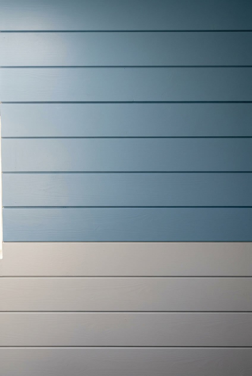 Interior wall of a camper with two-tone horizontal wooden panels in dusty blue and light gray.