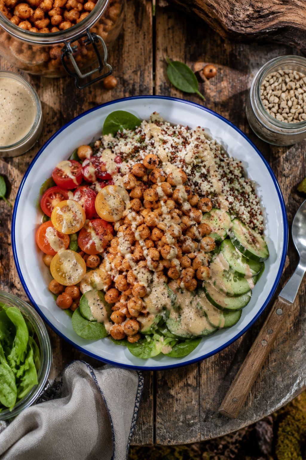Portrait/Pinterest format () showing a close-up overhead flat-lay of a vibrant grain bowl with quinoa, roasted chickpeas,